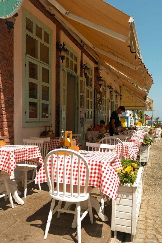 Sunny outdoor cafe with red checkered tables and white chairs, inviting for dining.
